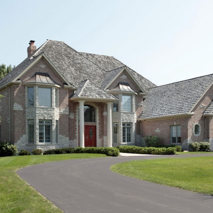 Steeply pitched residential roof with multiple dormer windows and complex roofline.