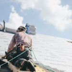 Roofer adding shingles to the roof of a house - featured image